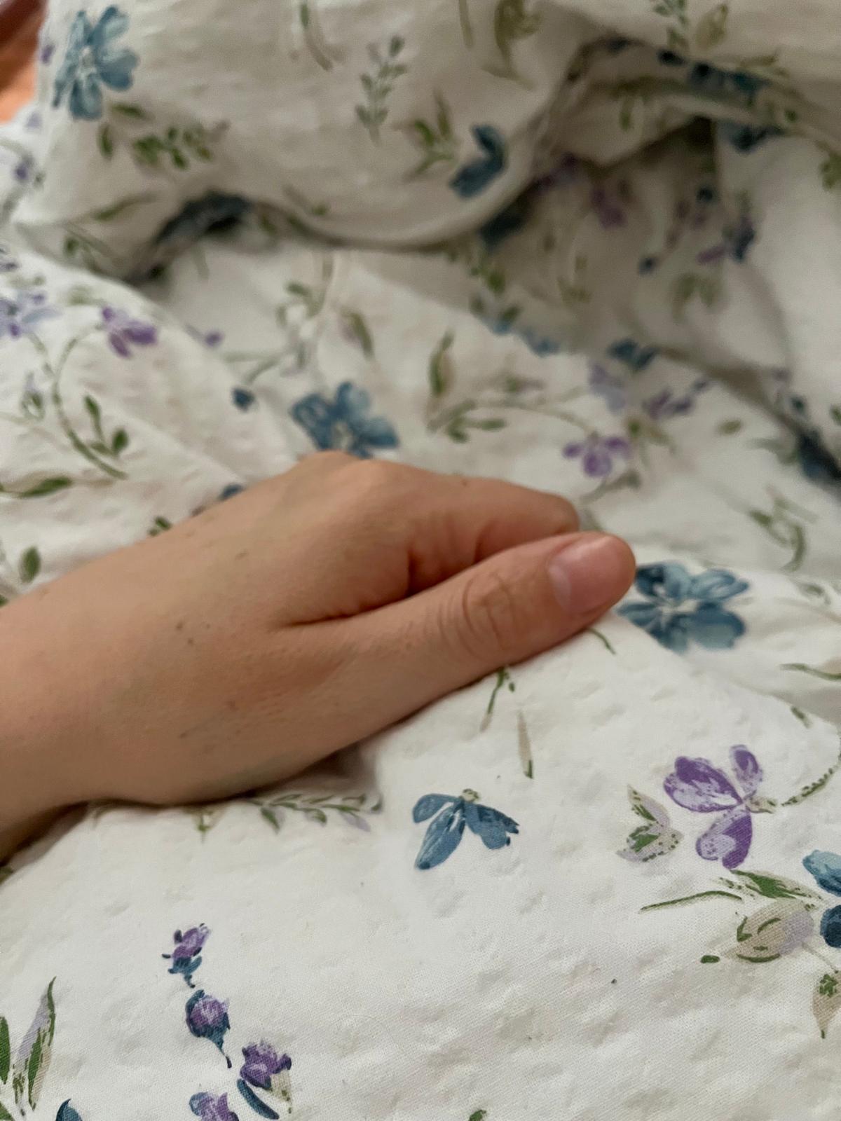 Ruka na měkké peřině — tichý, křehký okamžik