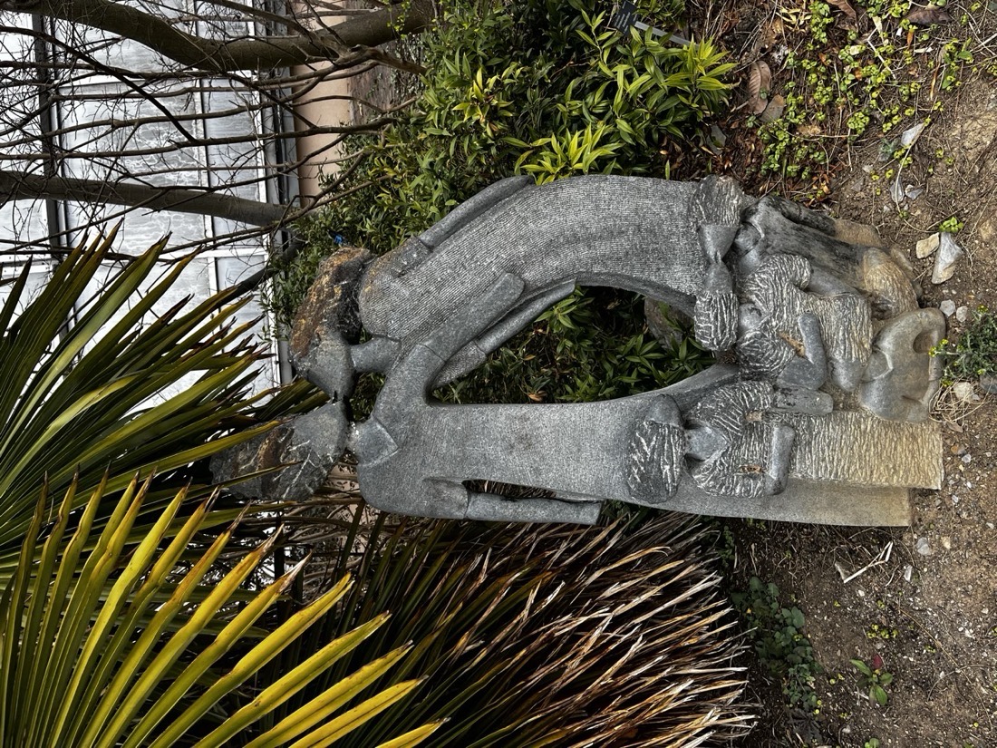 Kamenná socha v zahradě: dva dospělí v objetí a děti u jejich nohou